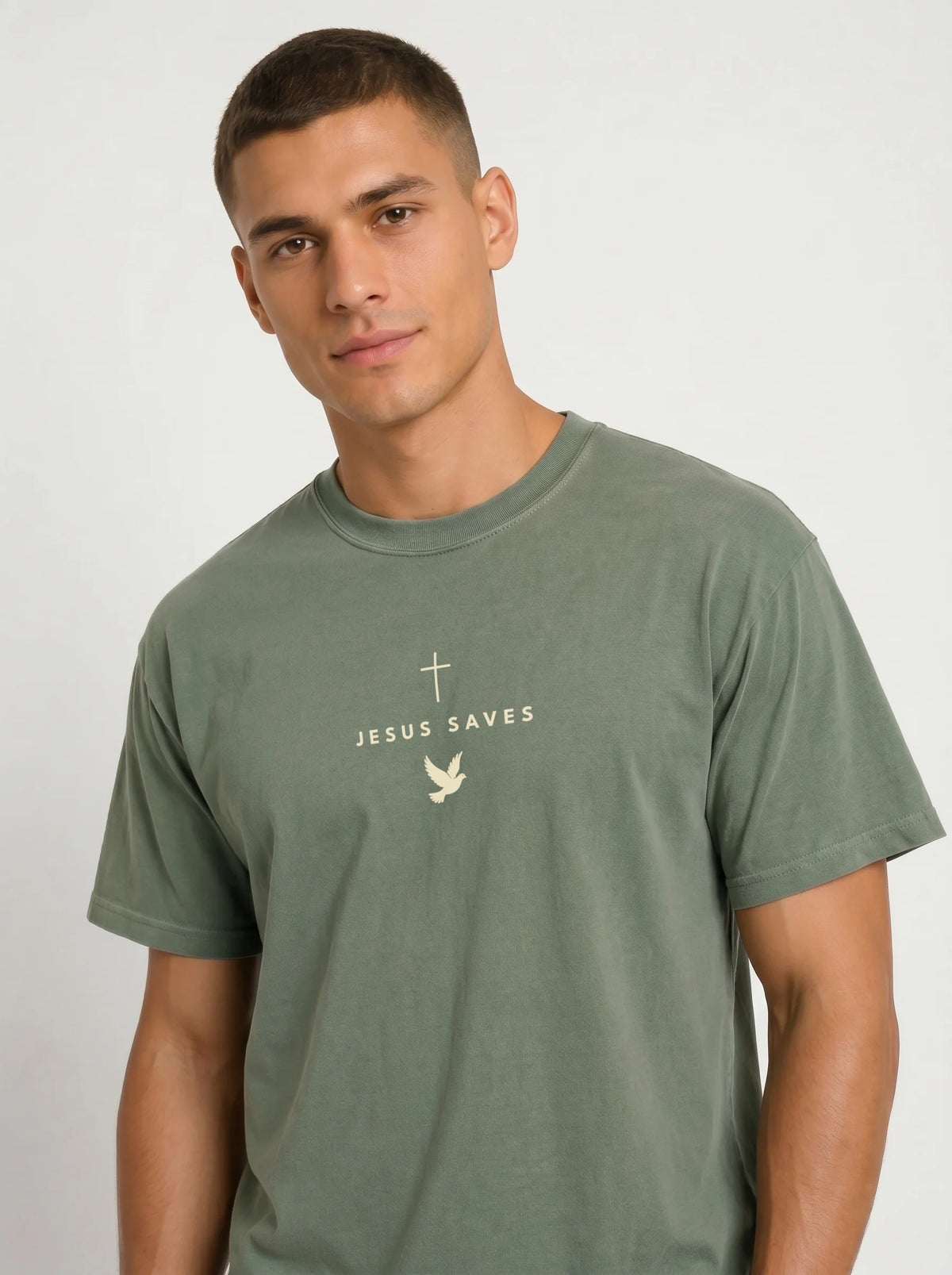 Person wearing a faded green T-shirt with a light cross, “JESUS SAVES” text, and dove graphic.