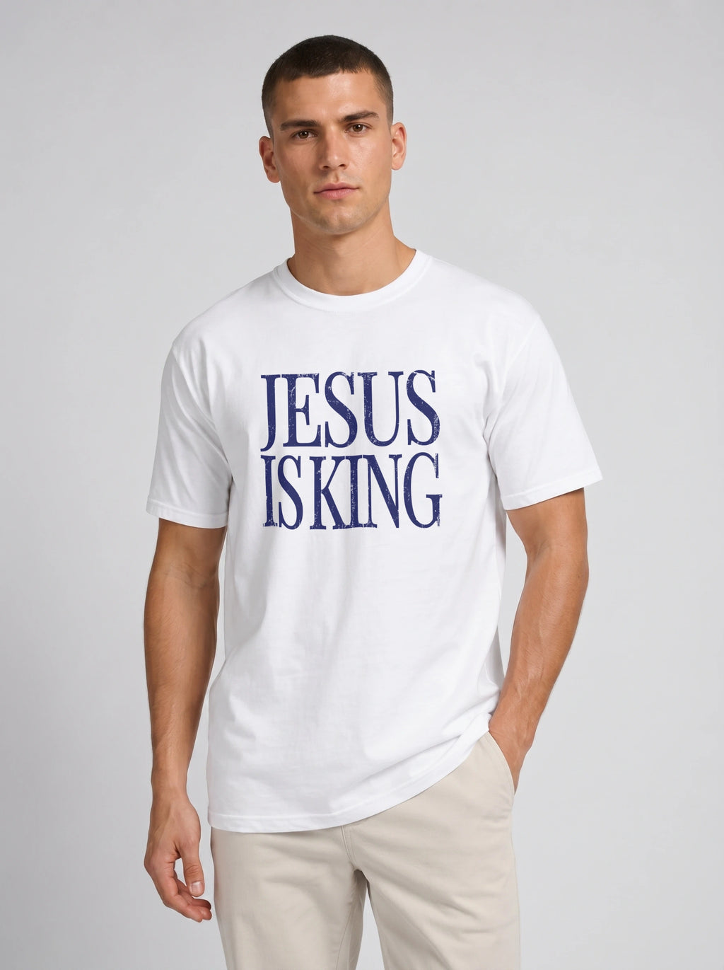 Person wearing a white T-shirt with distressed navy text reading “Jesus Is King.”