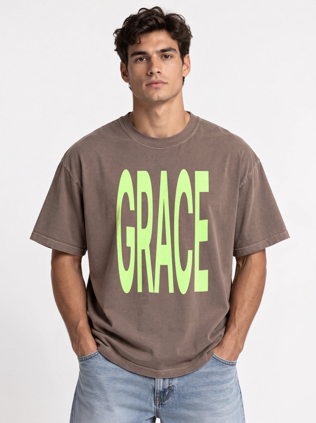 Person wearing a faded brown T-shirt with large neon green text reading “GRACE.”