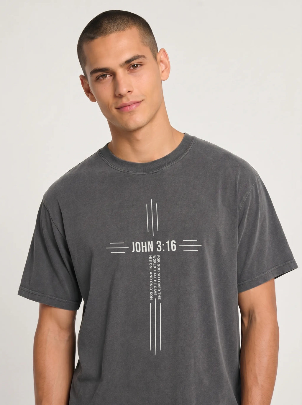 Person wearing a charcoal gray T-shirt with a white cross design reading “John 3:16” and “For God so loved the world that he gave his one and only son.”