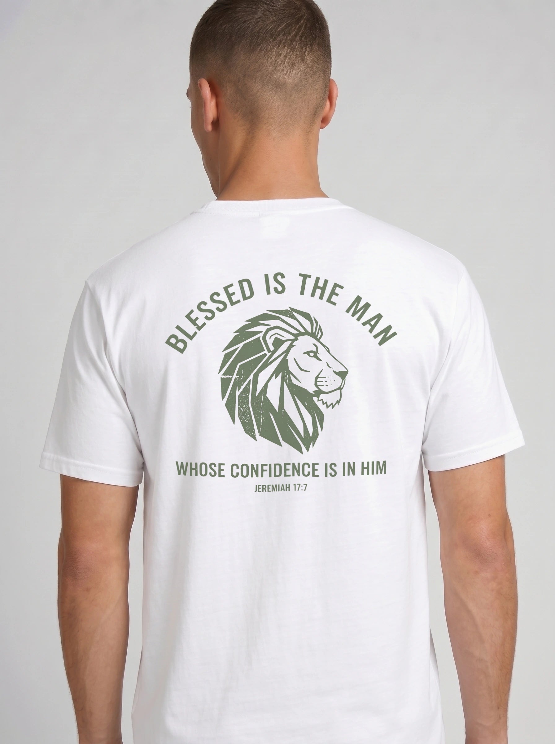 A man viewed from the back wearing a white short-sleeve t-shirt with a green graphic print featuring a lion head and the text 'BLESSED IS THE MAN WHOSE CONFIDENCE IS IN HIM'.