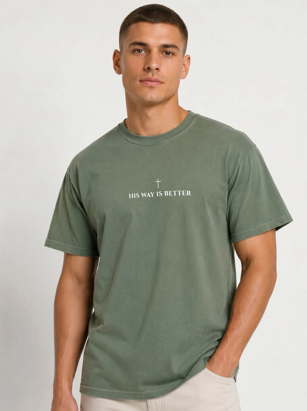 Person wearing a muted green T-shirt with a small cross above the text “His Way Is Better.”