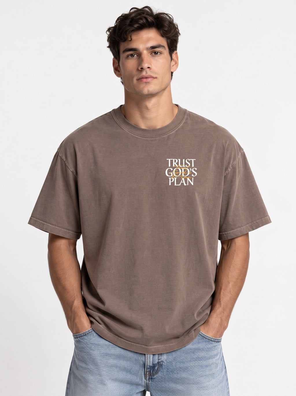Person wearing a faded brown T-shirt with a small chest design reading “TRUST GOD’S PLAN.”