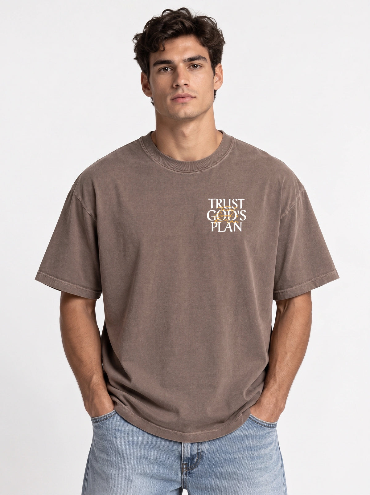 Person wearing a faded brown T-shirt with a small chest design reading “TRUST GOD’S PLAN.”