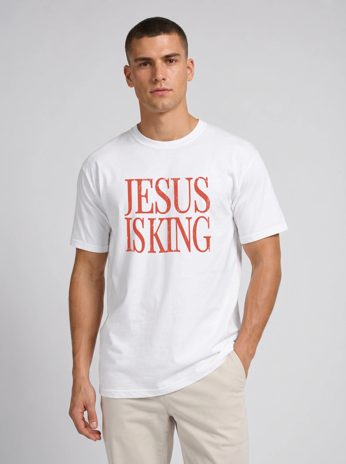 Person wearing a white T-shirt with distressed orange text reading “Jesus Is King.”