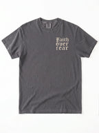 A dark gray crewneck t-shirt with the words 'Faith over fear' printed in a beige gothic font on the left chest, displayed flat against a white background.