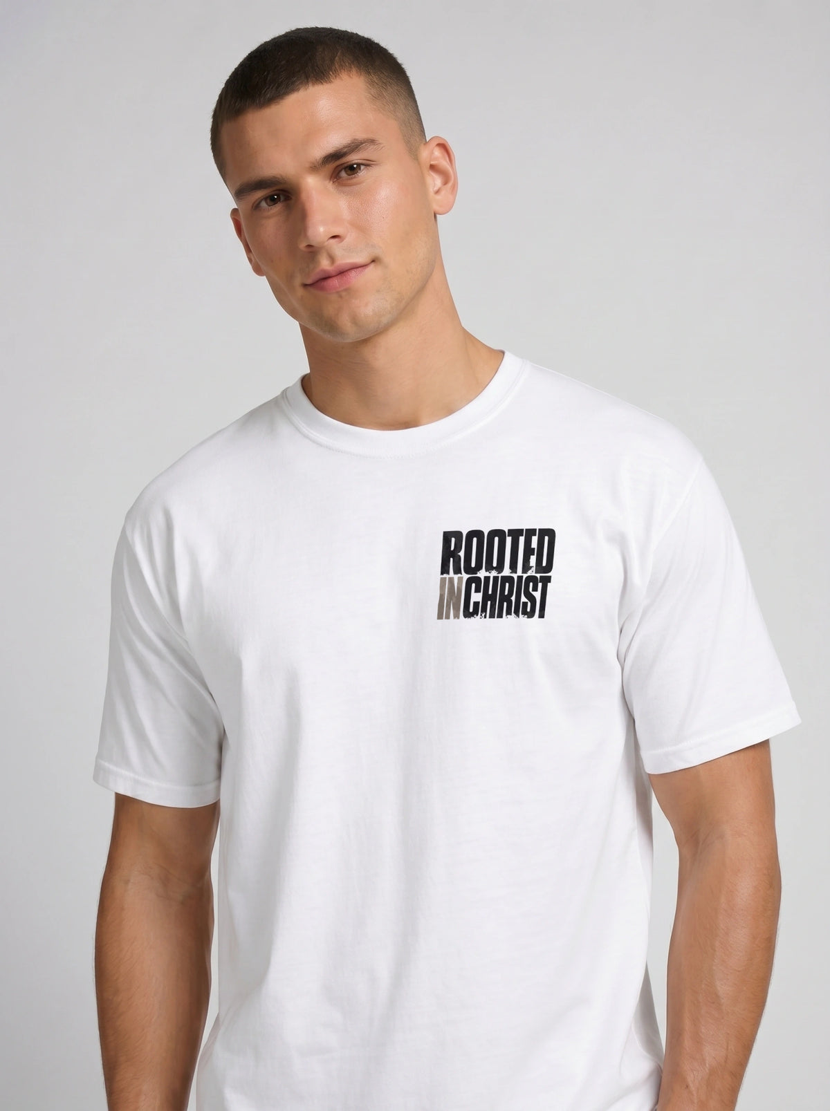 Person wearing a white T-shirt with a distressed chest print reading “Rooted in Christ.”
