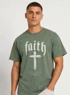 Person wearing a muted green T-shirt with “faith,” a large cross, and the text “1 Corinthians 16:13 — Be watchful. Stand firm in the faith. Be strong.”