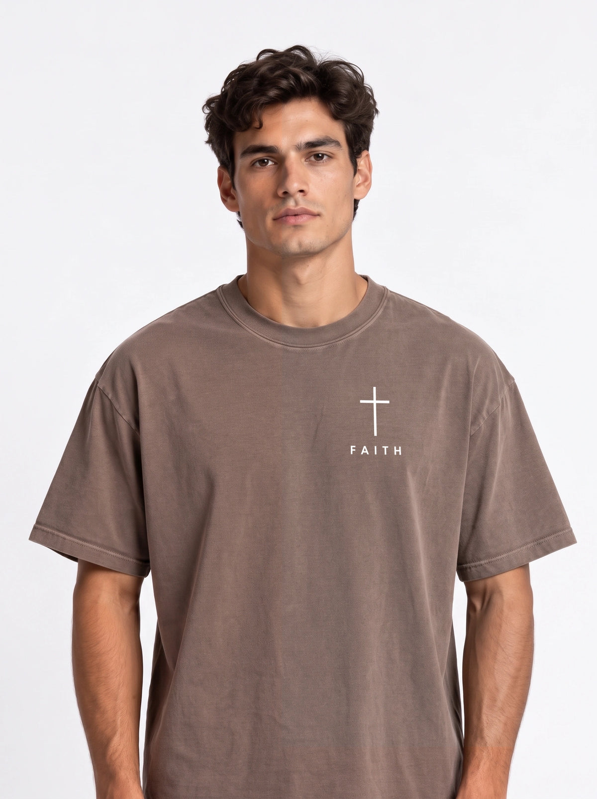 Person wearing a faded brown T-shirt with a white cross and “FAITH” printed on the chest.