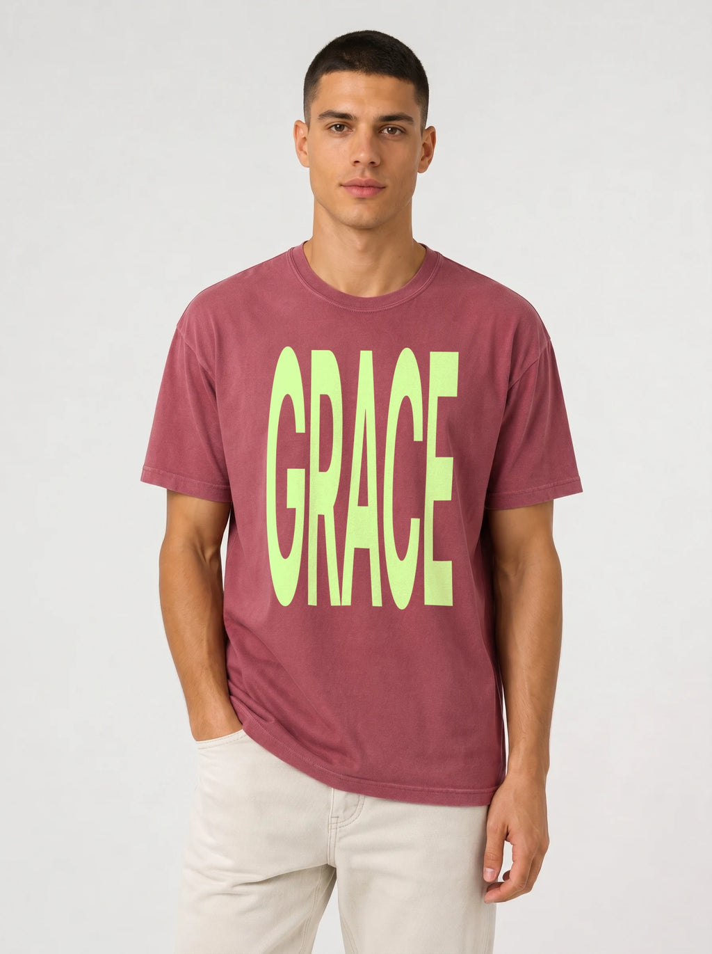 Person wearing a faded red T-shirt with large neon green text reading “GRACE.”