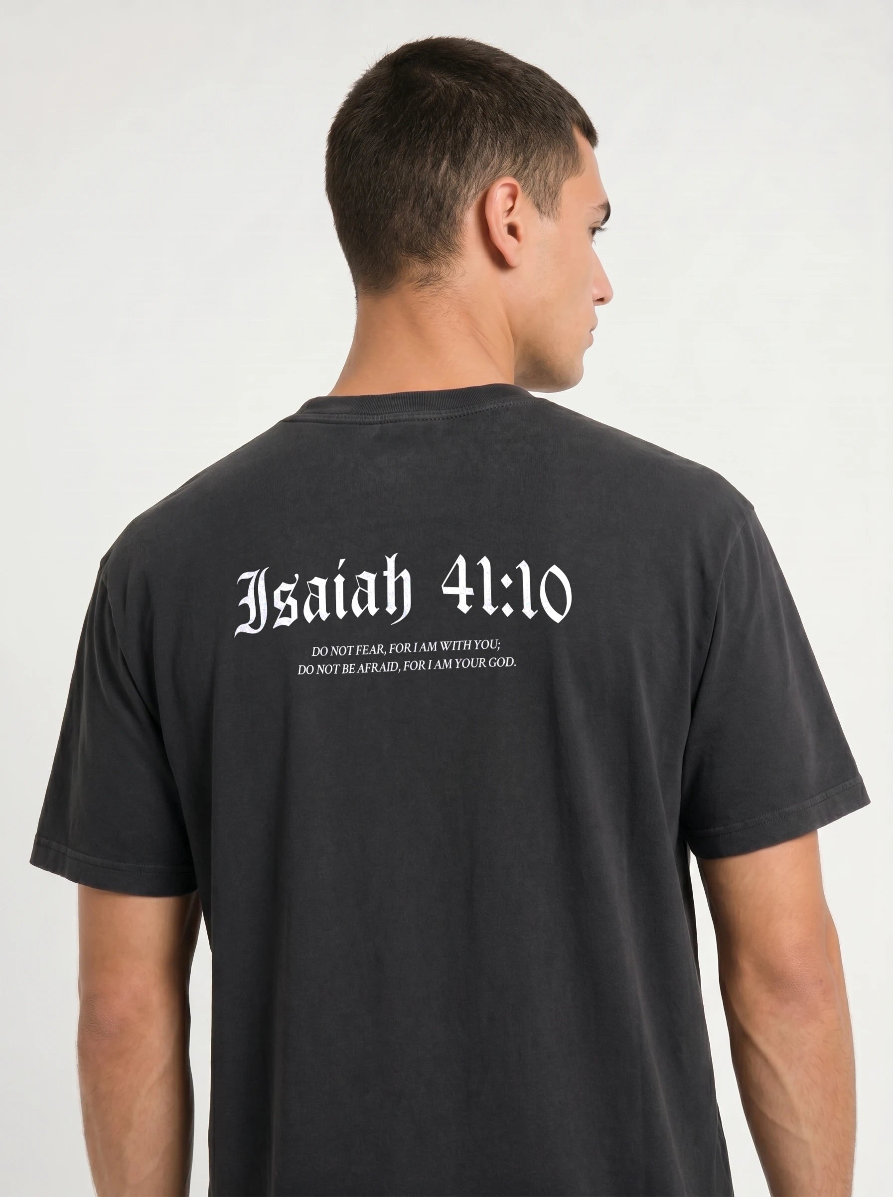 A man shown from the back wearing a black t-shirt with 'Isaiah 41:10' printed in white gothic font across the upper back.