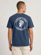 A man viewed from the back wearing a navy blue t-shirt with a large white circular graphic on the back that reads 'Salvation & Spirit Ephesians 6:17' around a helmet design.