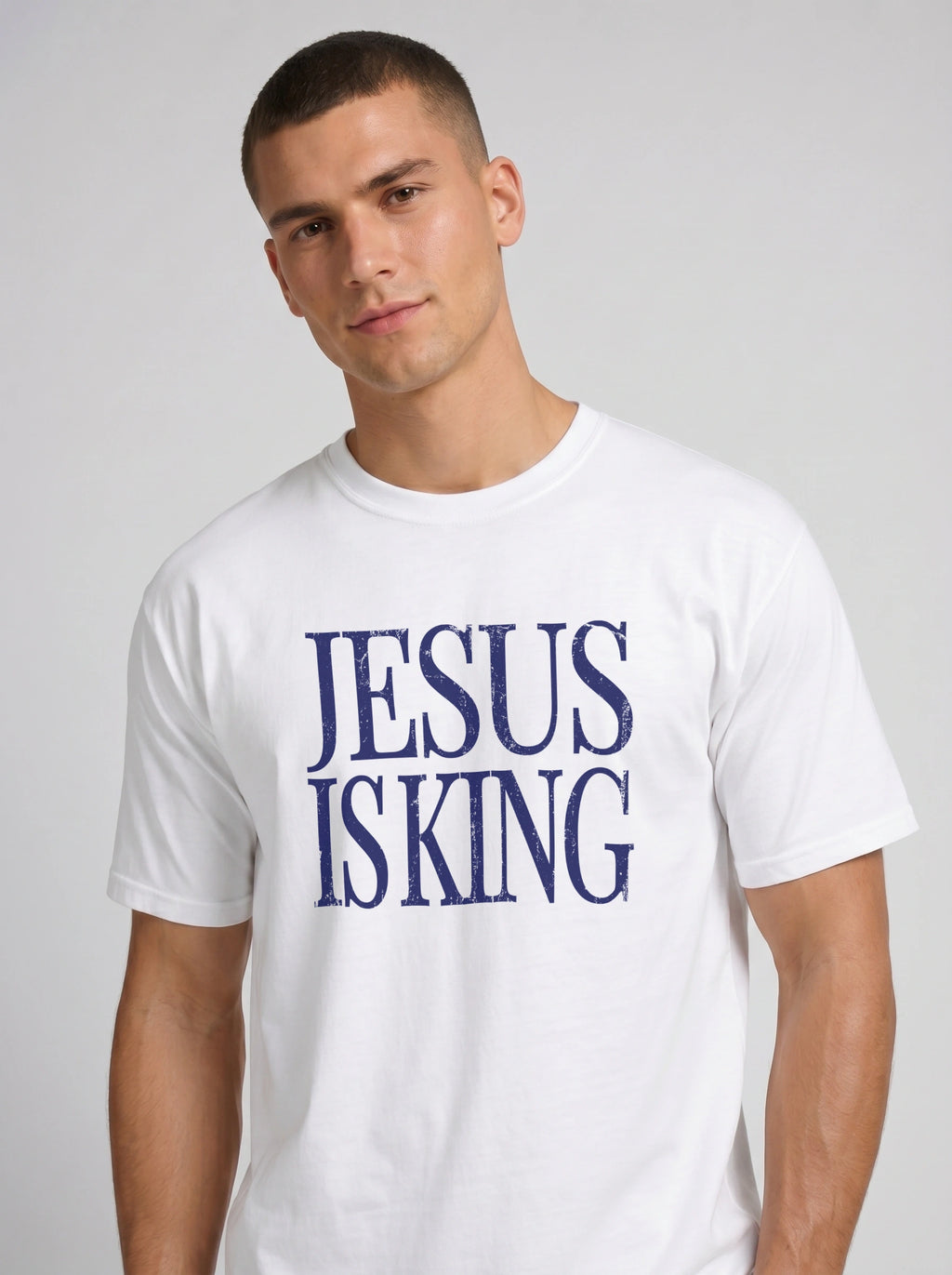 Person wearing a white T-shirt with distressed navy text reading “Jesus Is King.”