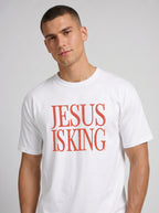 Person wearing a white T-shirt with distressed orange text reading “Jesus Is King.”