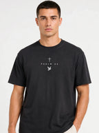 Person wearing a faded black T-shirt with a light cross, “PSALM 23” text, and dove graphic.