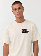 Person wearing a cream T-shirt with a distressed chest print reading “To Him Be Glory.”