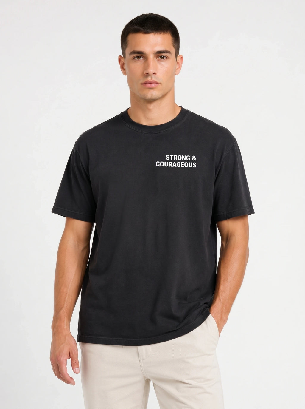 Person wearing a black T-shirt with small white chest text reading “Strong & courageous.”