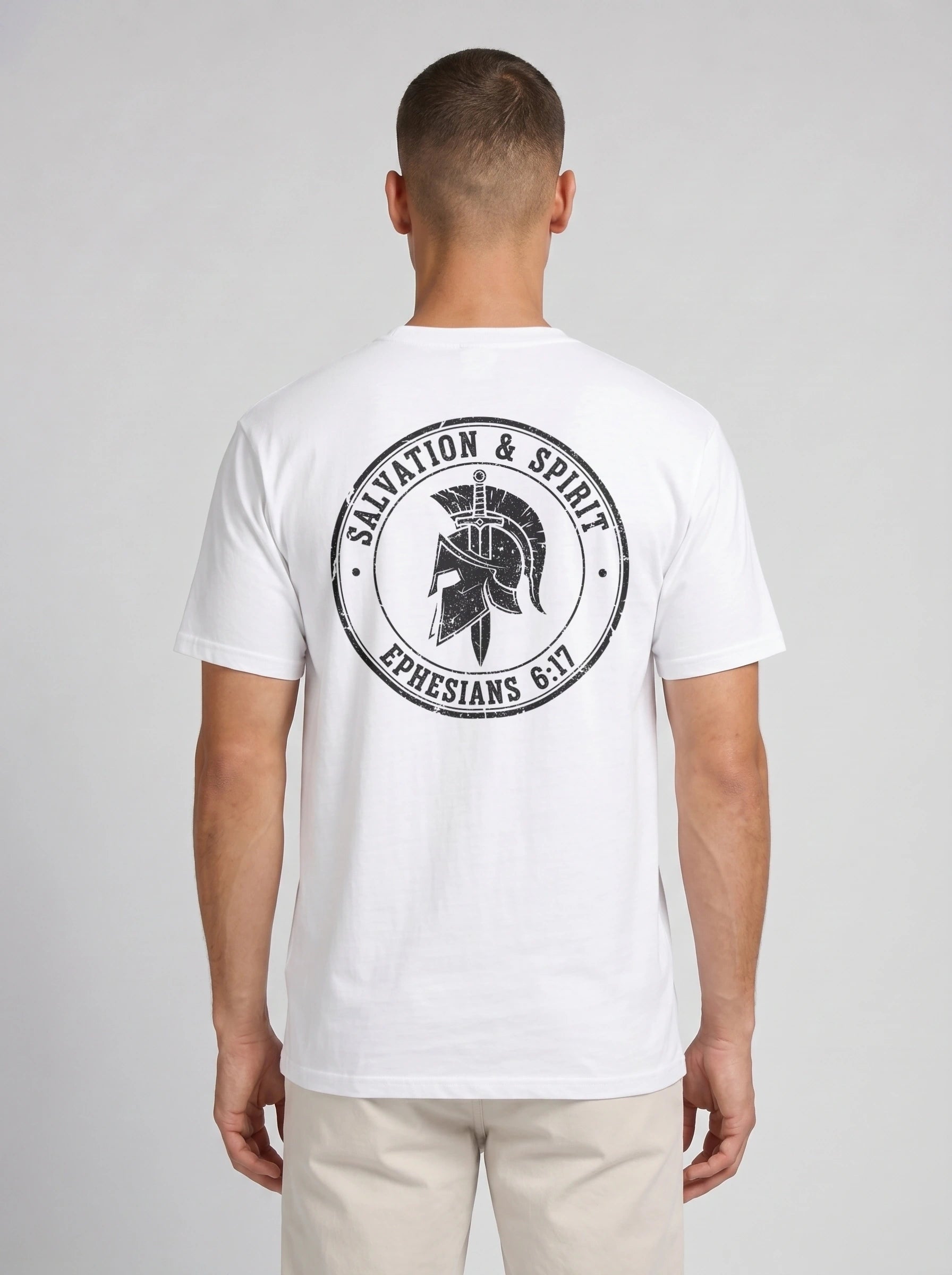 A man viewed from the back wearing a white short-sleeve t-shirt with a large black circular graphic on the back featuring a gladiator helmet and the text 'SALVATION & SPIRIT' and 'EPHESIANS 6:17'.