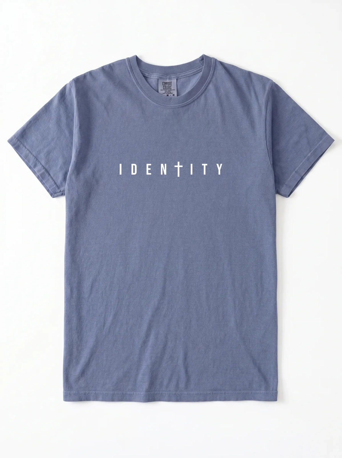 Faded blue T-shirt laid flat with “IDENTITY,” the second T stylized as a cross, printed across the chest.