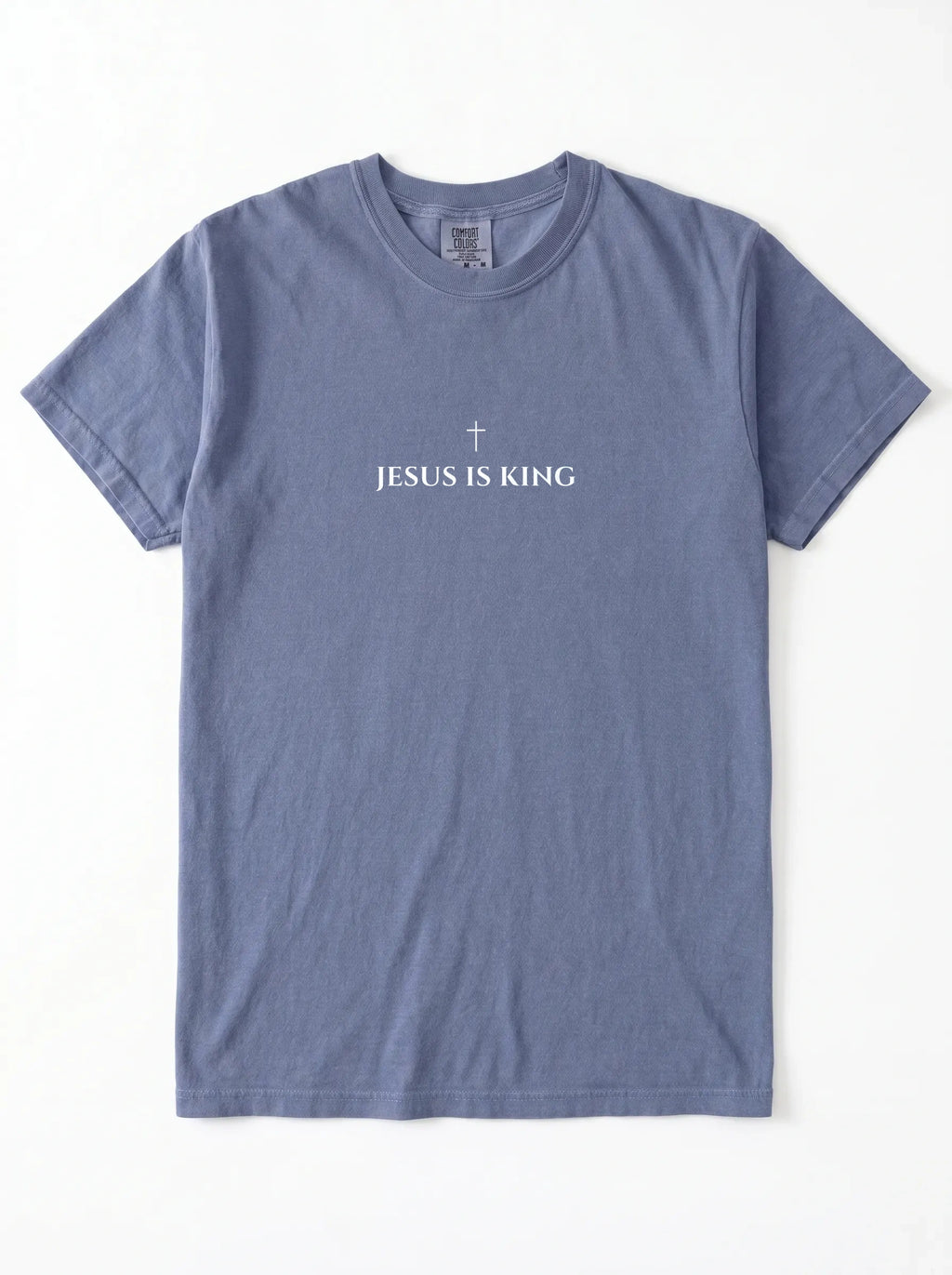 Muted blue T-shirt laid flat with a small cross above the text “Jesus Is King.”