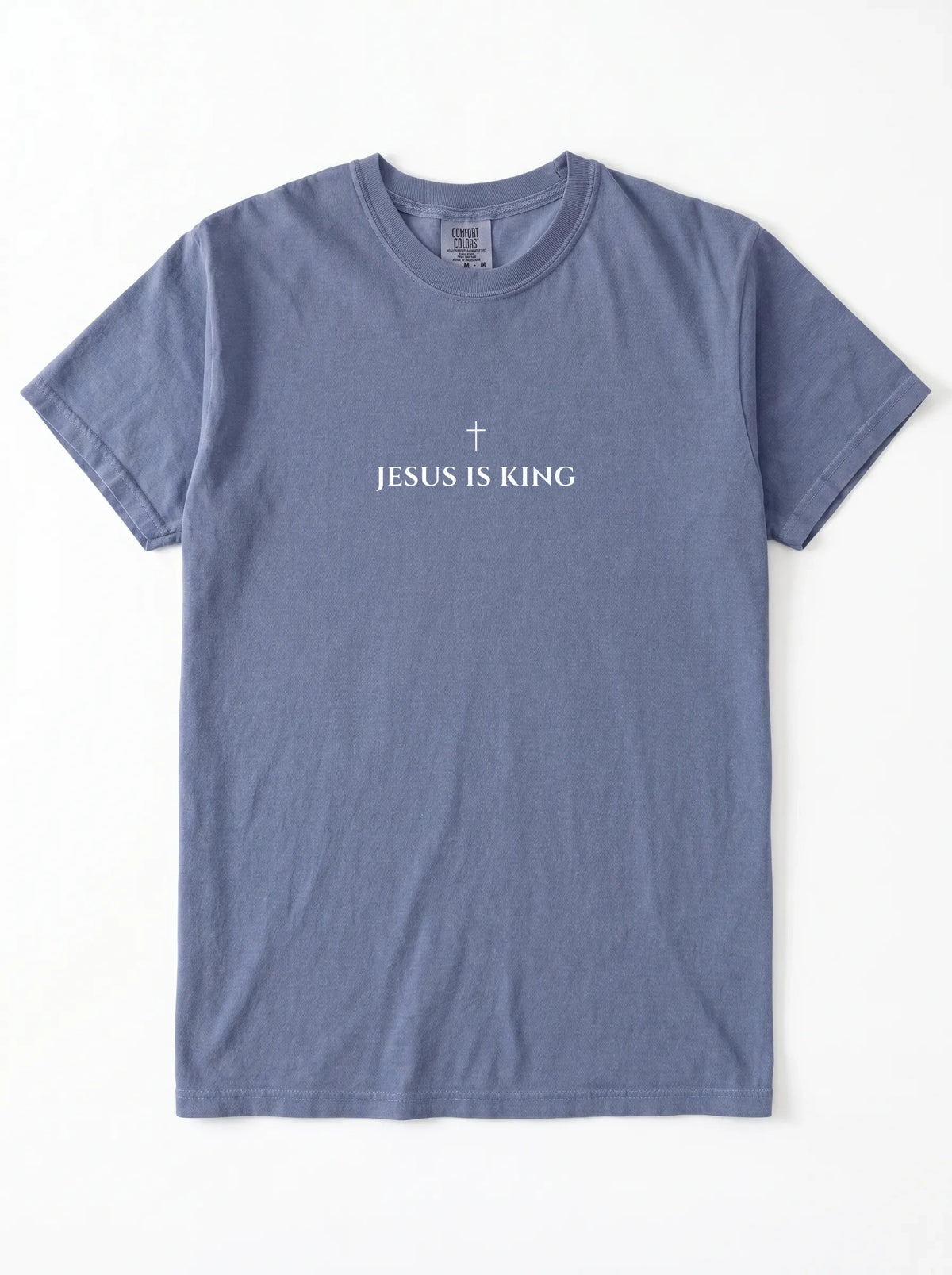 Muted blue T-shirt laid flat with a small cross above the text “Jesus Is King.”
