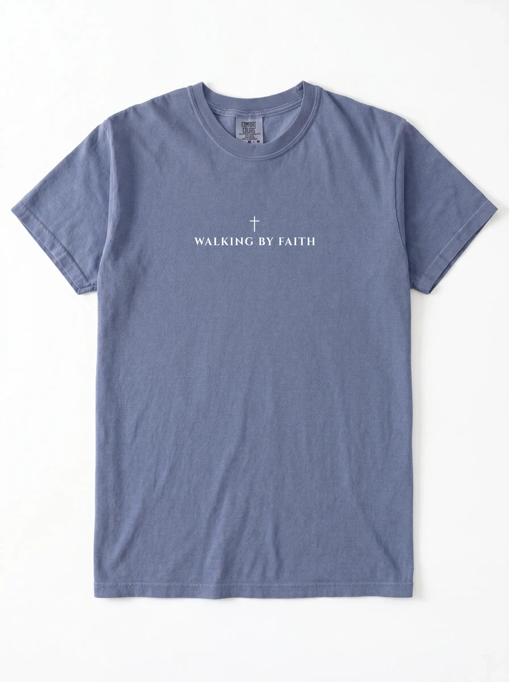 A heathered slate blue short-sleeve t-shirt with 'WALKING BY FAITH' and a small cross printed in white on the chest, laid flat against a white background.