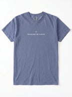 A heathered slate blue short-sleeve t-shirt with 'WALKING BY FAITH' and a small cross printed in white on the chest, laid flat against a white background.