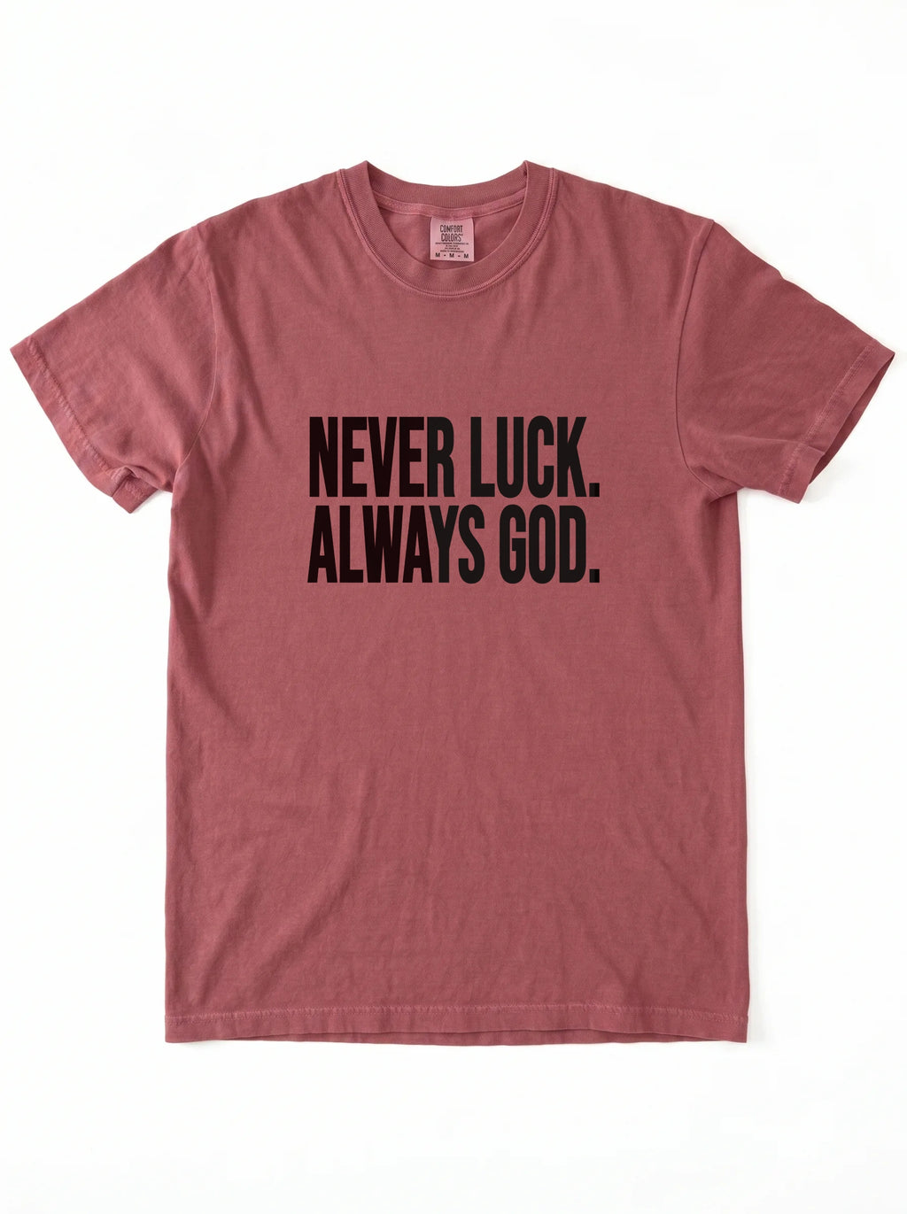 Faded red T-shirt laid flat with black text reading “Never luck. Always God.”