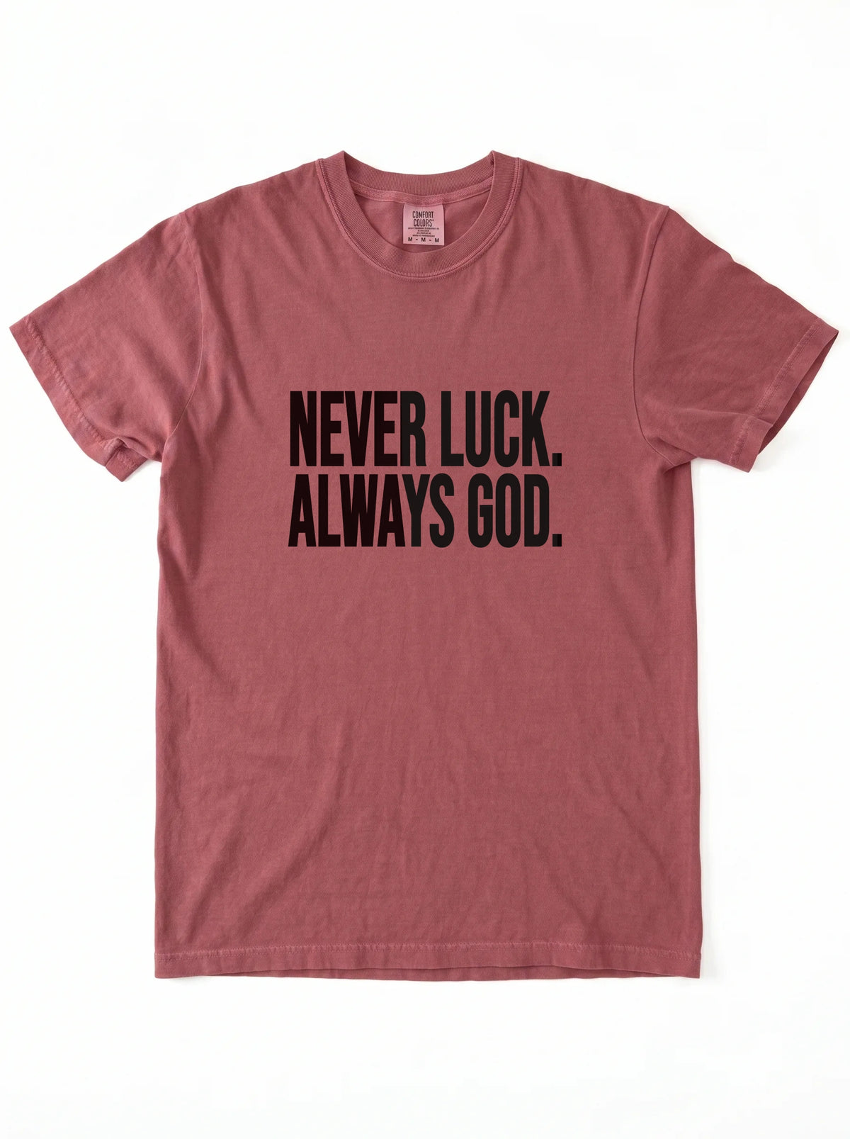 Faded red T-shirt laid flat with black text reading “Never luck. Always God.”