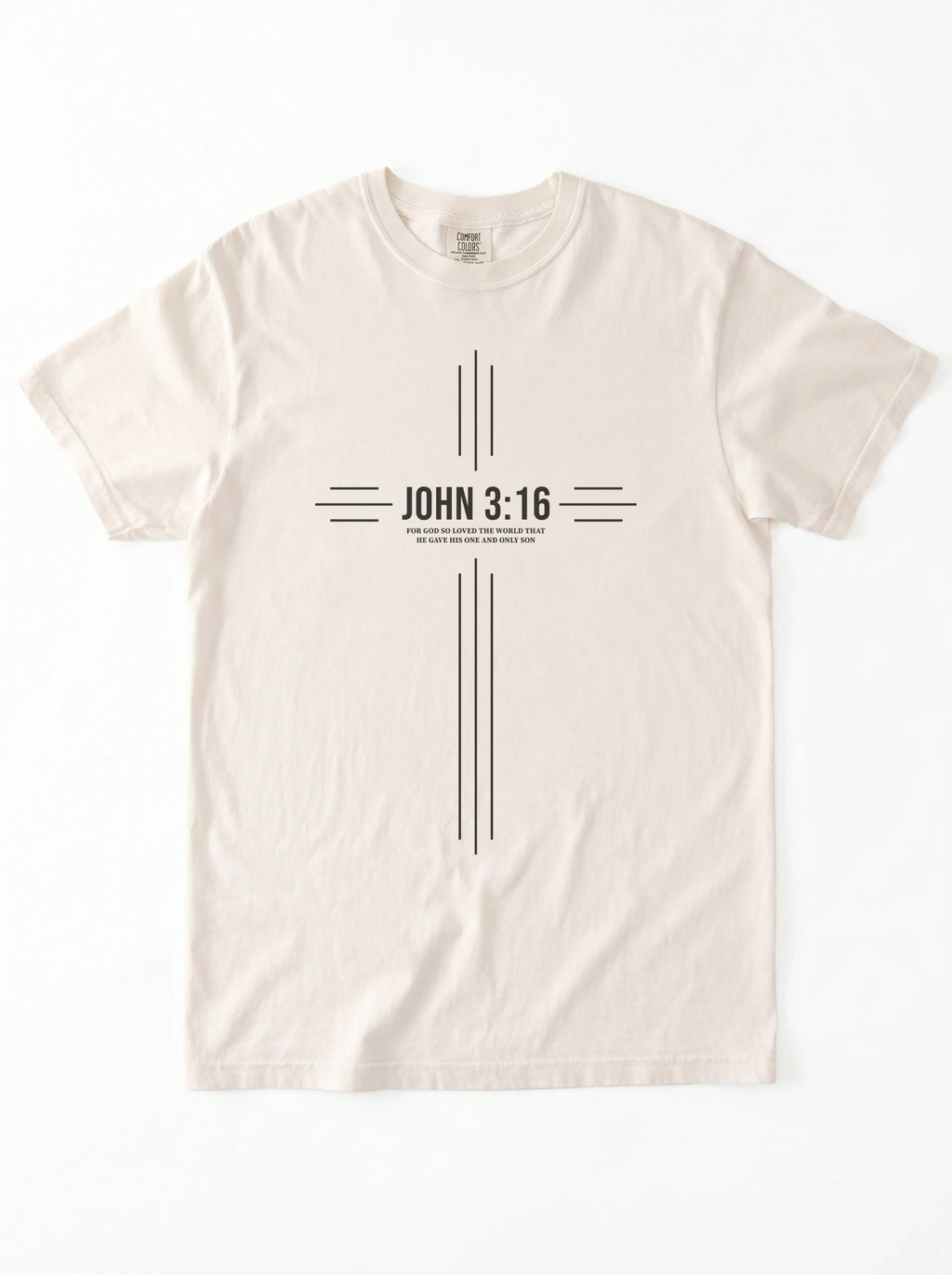 Cream T-shirt laid flat with a black cross-shaped design reading “John 3:16” and “For God so loved the world that he gave his one and only son.”