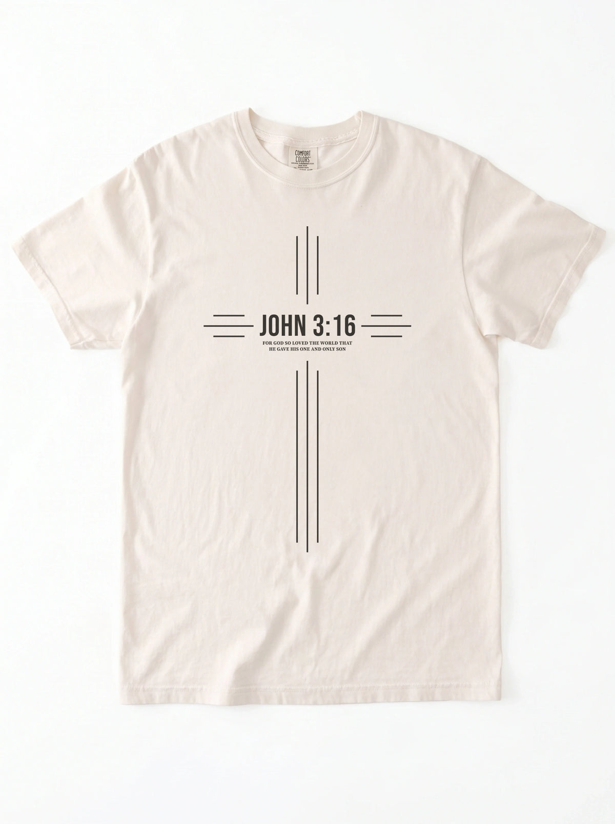 Cream T-shirt laid flat with a black cross-shaped design reading “John 3:16” and “For God so loved the world that he gave his one and only son.”
