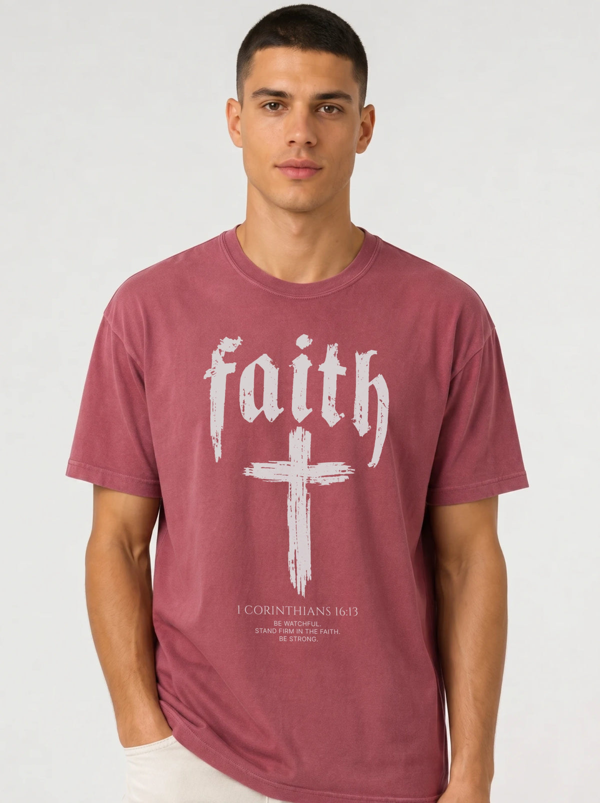 Person wearing a muted red T-shirt with “faith,” a large cross, and the text “1 Corinthians 16:13 — Be watchful. Stand firm in the faith. Be strong.”