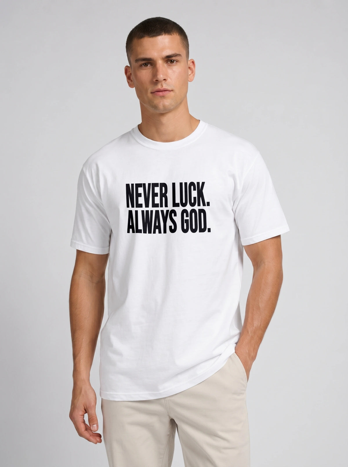 Person wearing a white T-shirt with black text reading “Never luck. Always God.”