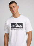 A man wearing a white crewneck t-shirt with a black graphic of mountains and the text 'FAITH CAN MOVE MOUNTAINS' printed on the chest, set against a plain light gray background.