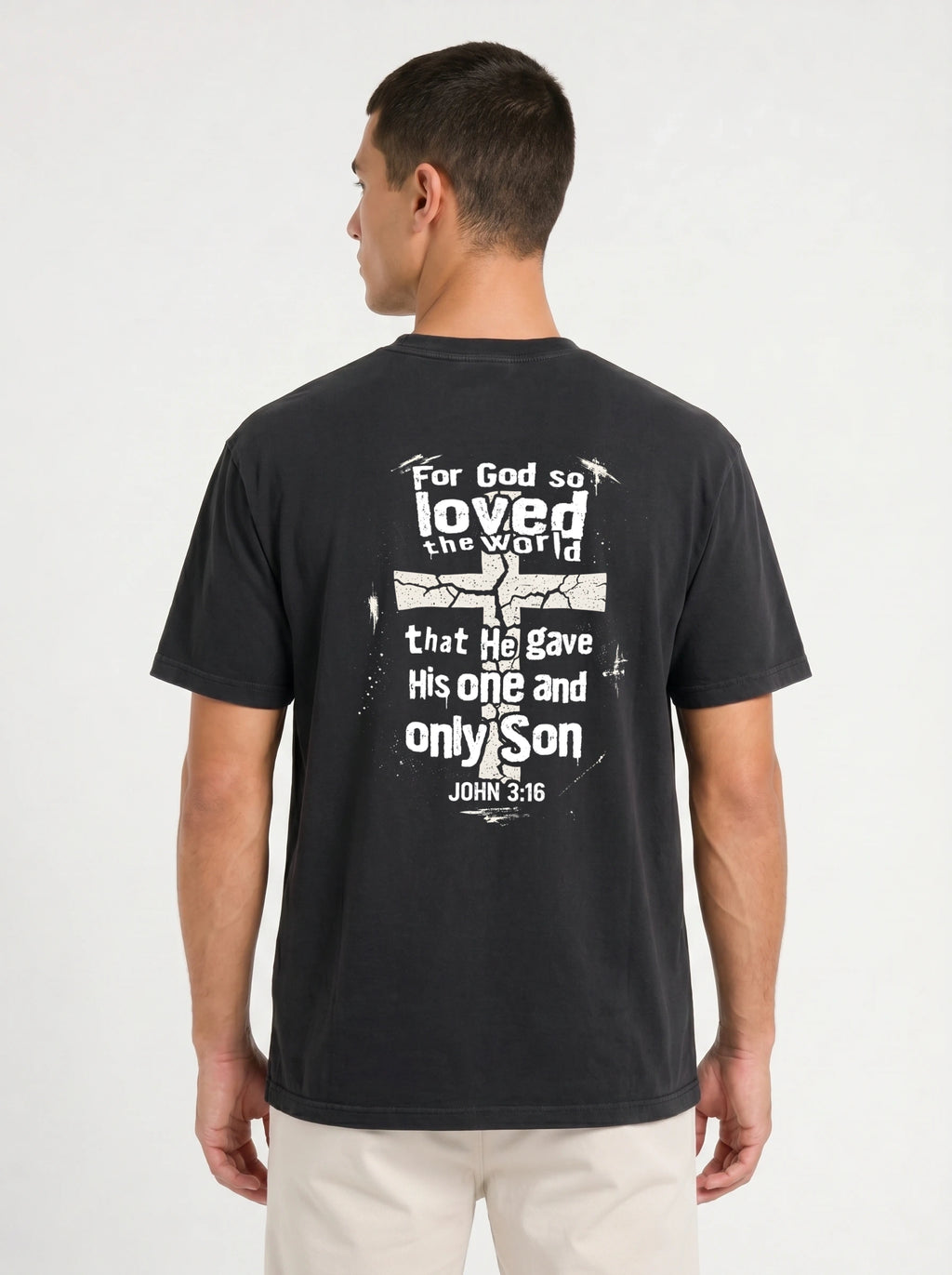 A man wearing a dark charcoal gray t-shirt, viewed from the back. The shirt features a distressed white graphic with the text 'For God so loved the world that He gave His one and only Son JOHN 3:16' surrounding a cracked cross design.