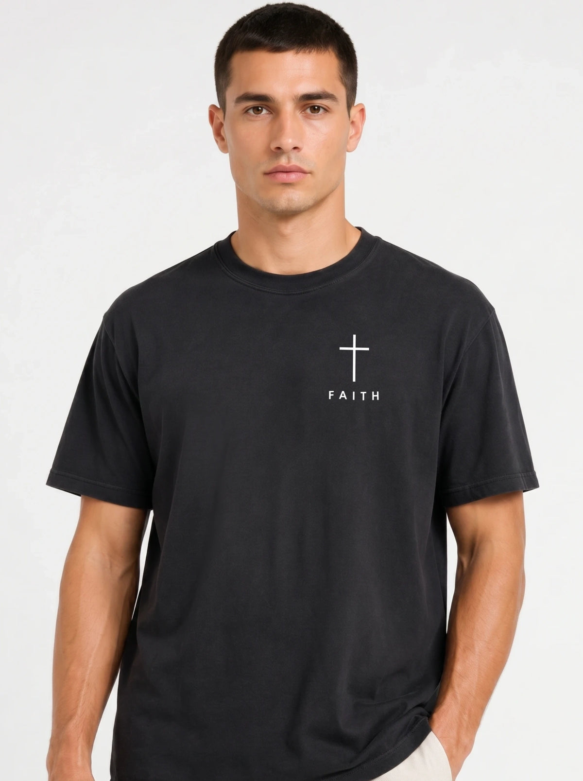Person wearing a faded black T-shirt with a white cross and “FAITH” printed on the chest.