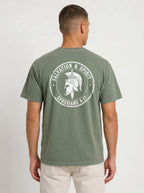 A man viewed from the back wearing an olive green t-shirt with a large white graphic print on the back featuring a Spartan helmet and the text 'SALVATION & SPIRIT' and 'EPHESIANS 6:17'.