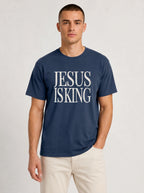 Person wearing a navy blue T-shirt with distressed cream text reading “Jesus Is King.”