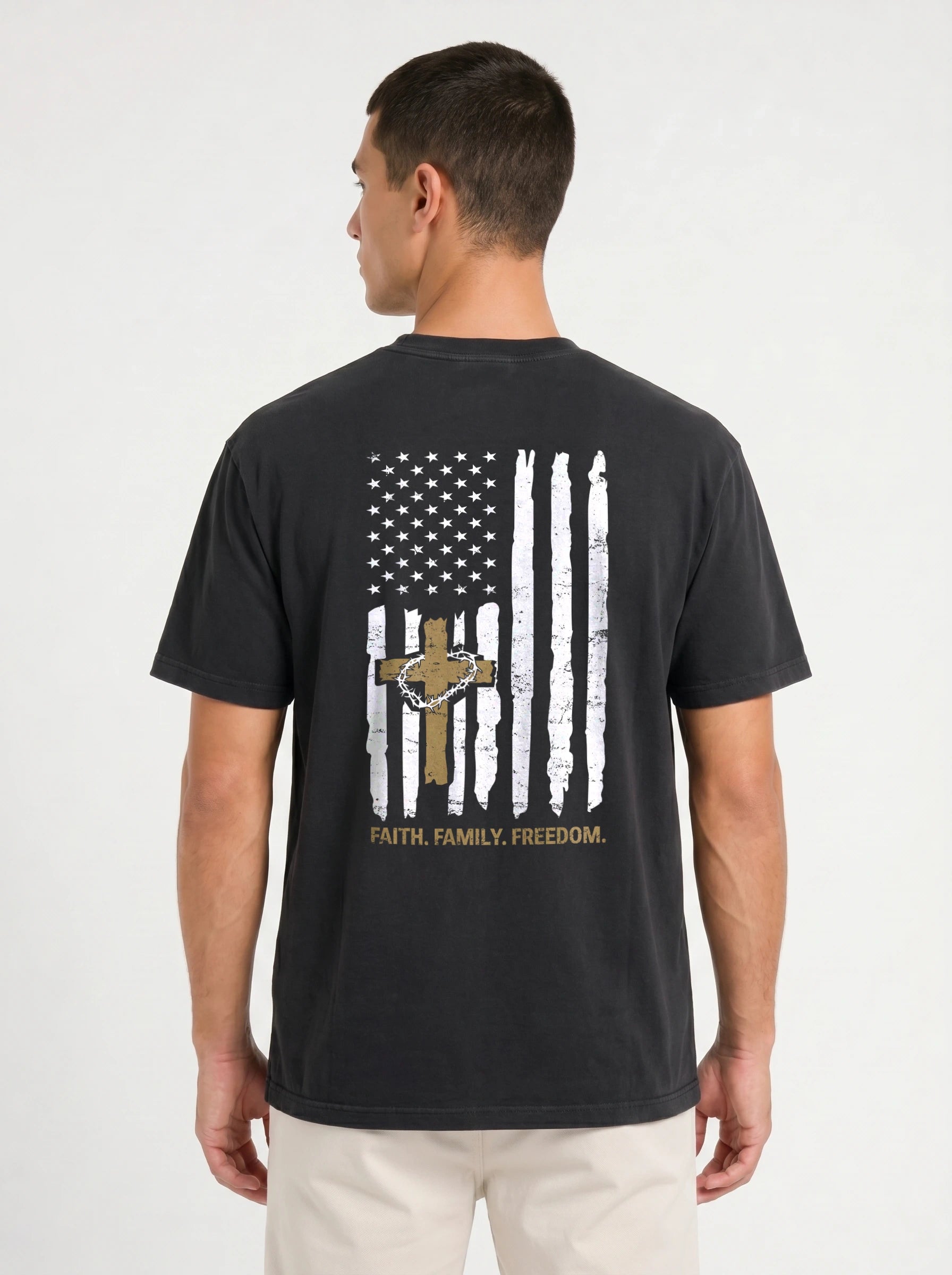 A man wearing a black t-shirt from the back, featuring a distressed white and gold American flag graphic with a cross and the text 'FAITH, FAMILY, FREEDOM.'.