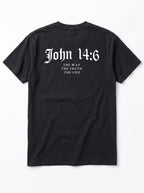 A black short-sleeve t-shirt shown from the back, featuring the text 'John 14:6' in a white Gothic font, with 'THE WAY THE TRUTH THE LIFE' printed below in a smaller serif font, on a light gray background.