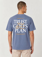 Person wearing a faded blue T-shirt with a large back design reading “JEREMIAH 29:11” and “TRUST GOD’S PLAN,” with the verse below.