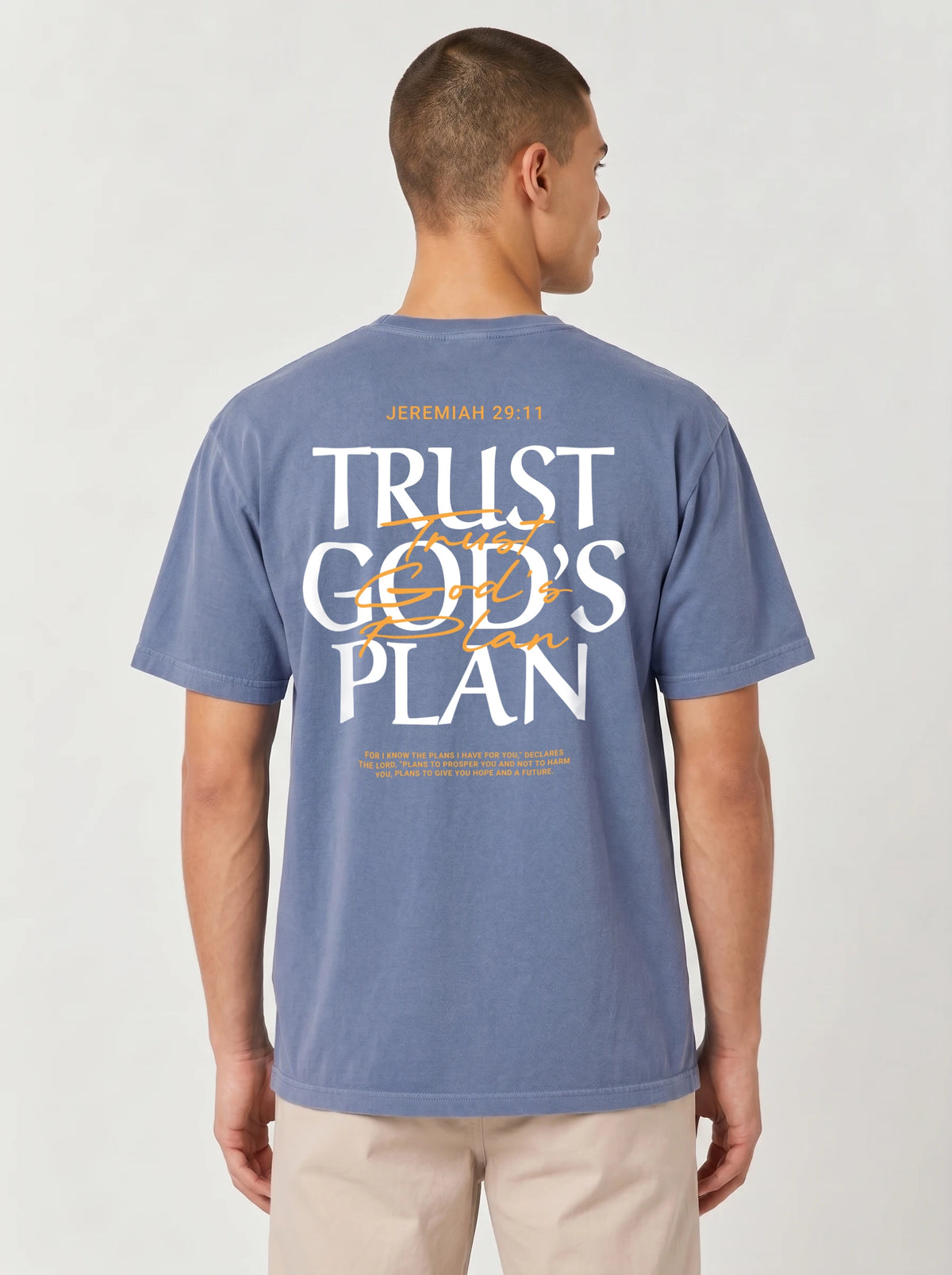 Person wearing a faded blue T-shirt with a large back design reading “JEREMIAH 29:11” and “TRUST GOD’S PLAN,” with the verse below.
