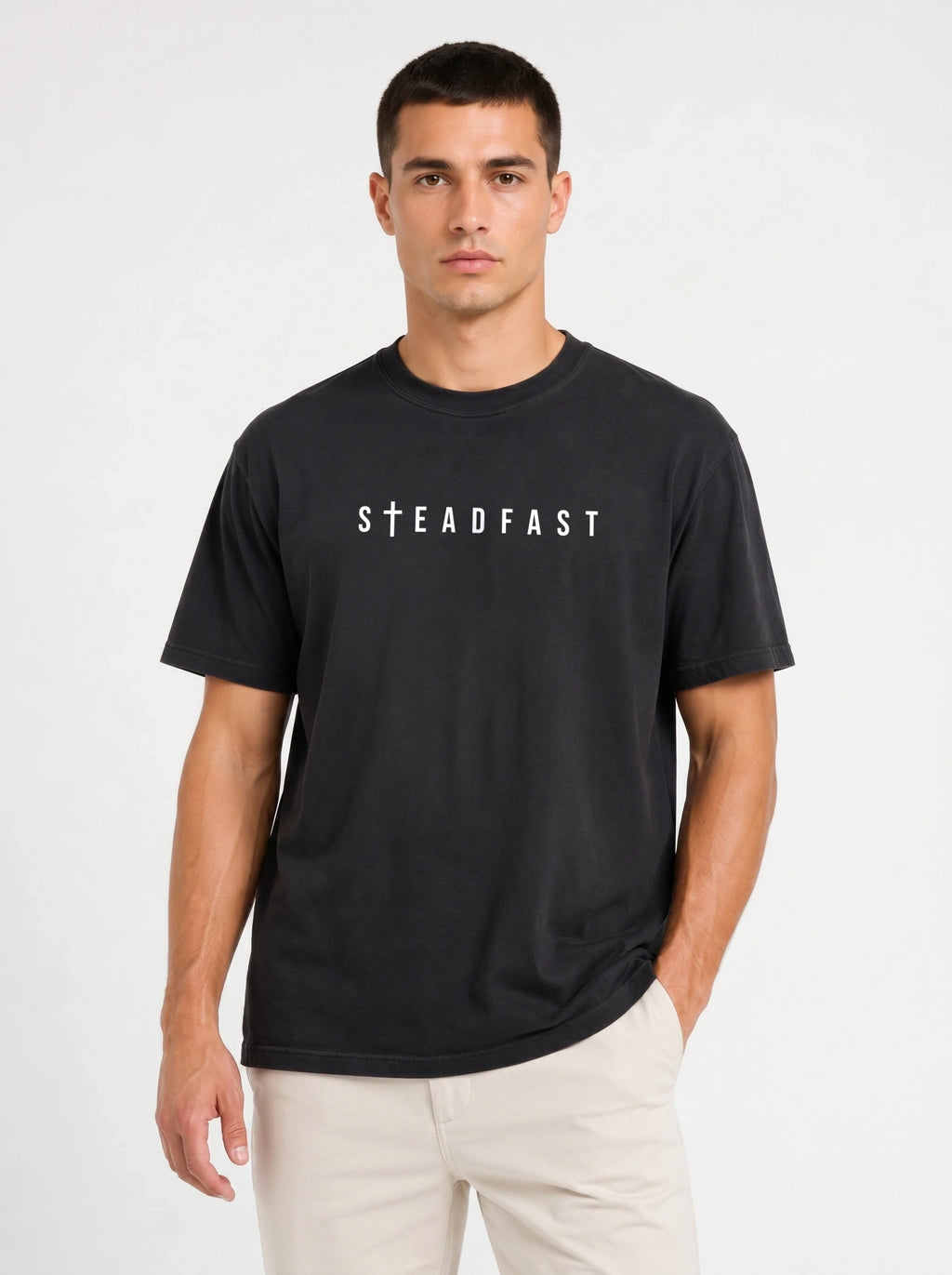 Person wearing a black T-shirt with white “Steadfast” text, featuring a cross in place of the letter T.