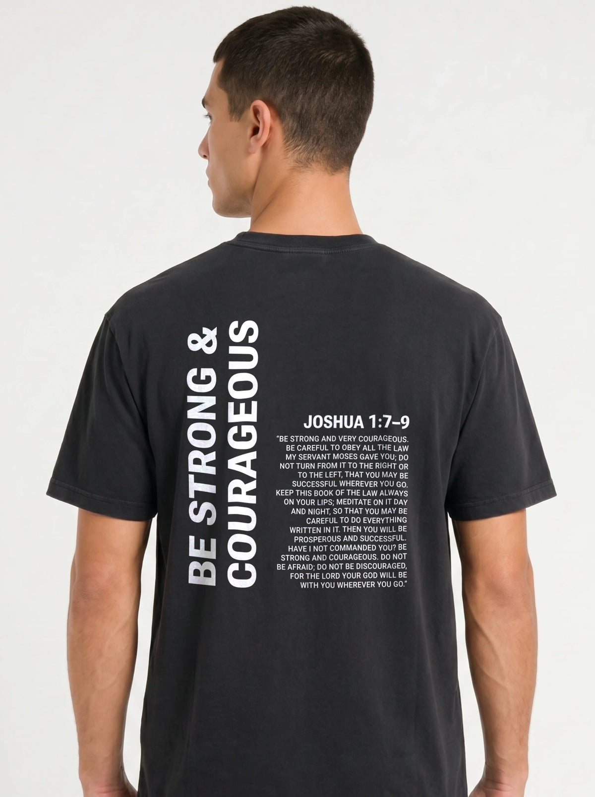 Person shown from behind in a black T-shirt with “Be strong & courageous” and Joshua 1:7–9 printed in white.