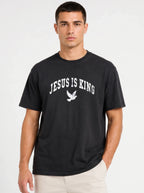 Person wearing a black T-shirt with distressed white “Jesus Is King” text and a flying dove graphic.