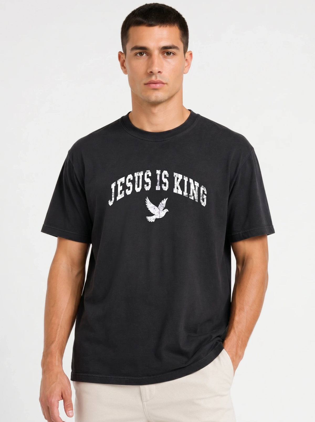 Person wearing a black T-shirt with distressed white “Jesus Is King” text and a flying dove graphic.