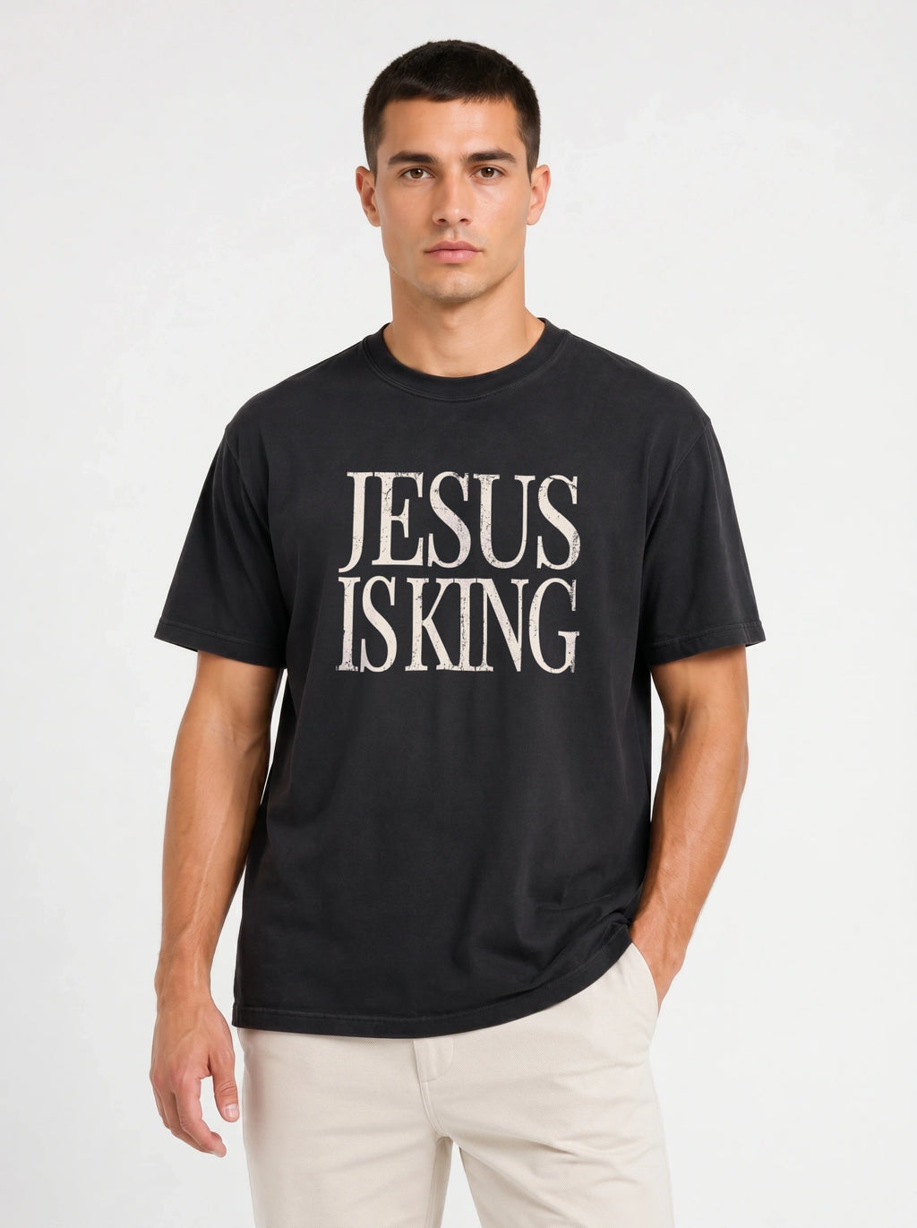 Person wearing a black T-shirt with distressed cream text reading “Jesus Is King.”