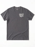 Front of a faded gray T-shirt with a small cream “Jesus is King” design on the left chest.