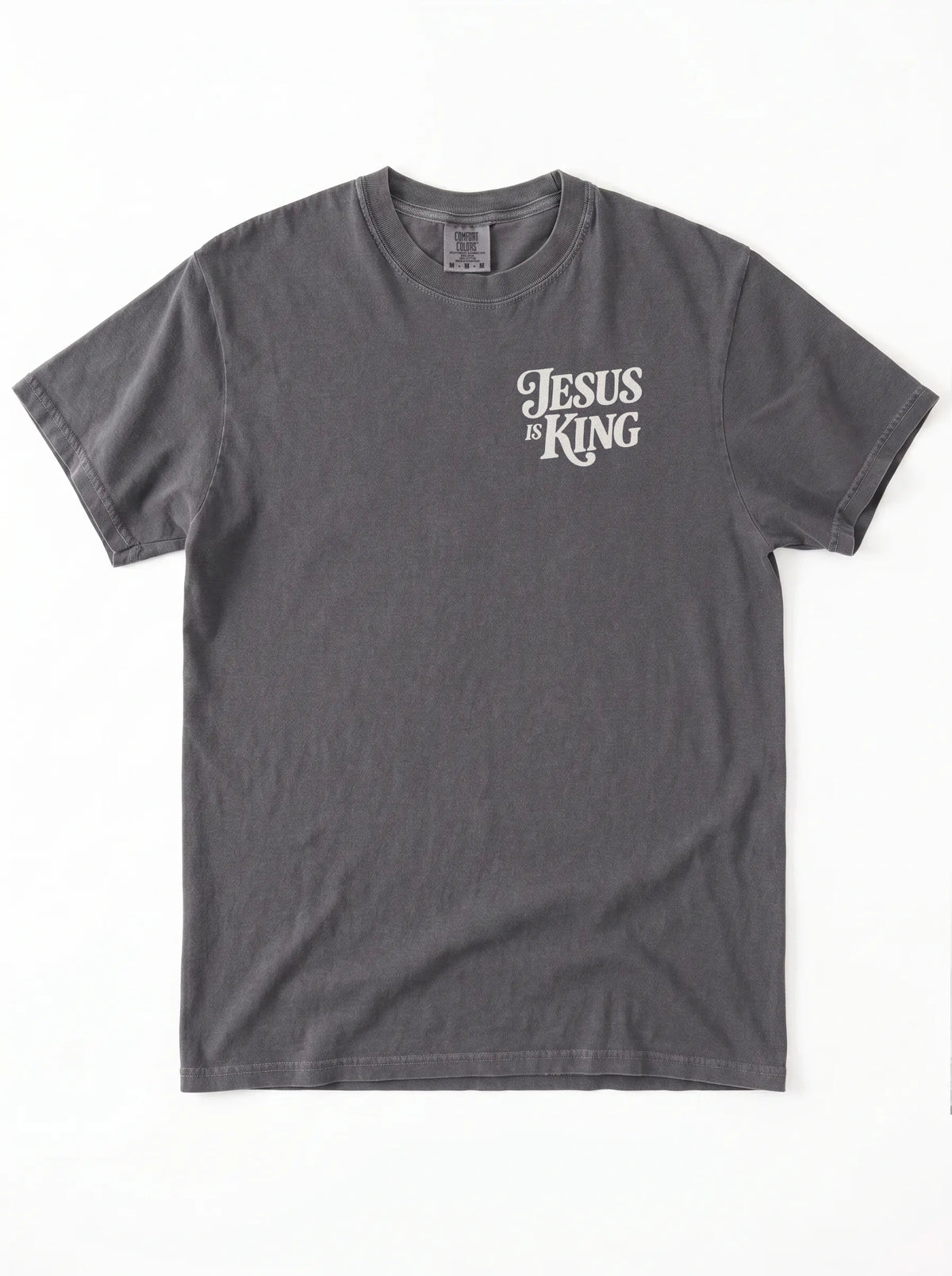 Front of a faded gray T-shirt with a small cream “Jesus is King” design on the left chest.