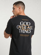 Person wearing a black T-shirt with “Ephesians 4:6,” a large white and orange “God Over All Things” back graphic, and Bible verse text.